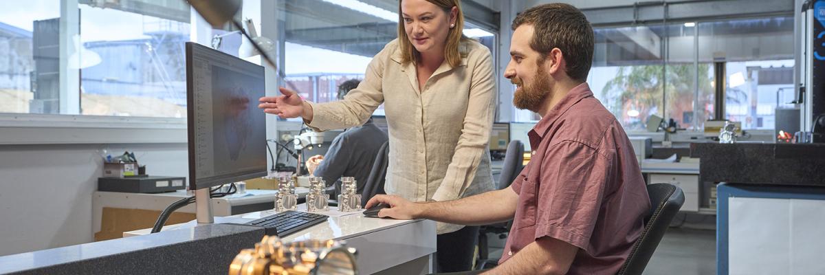 Women and man looking at computer screen smiling. 