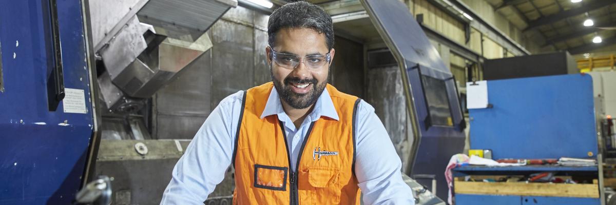 Hofmann Engineering employee smiling and holding CAD drawings