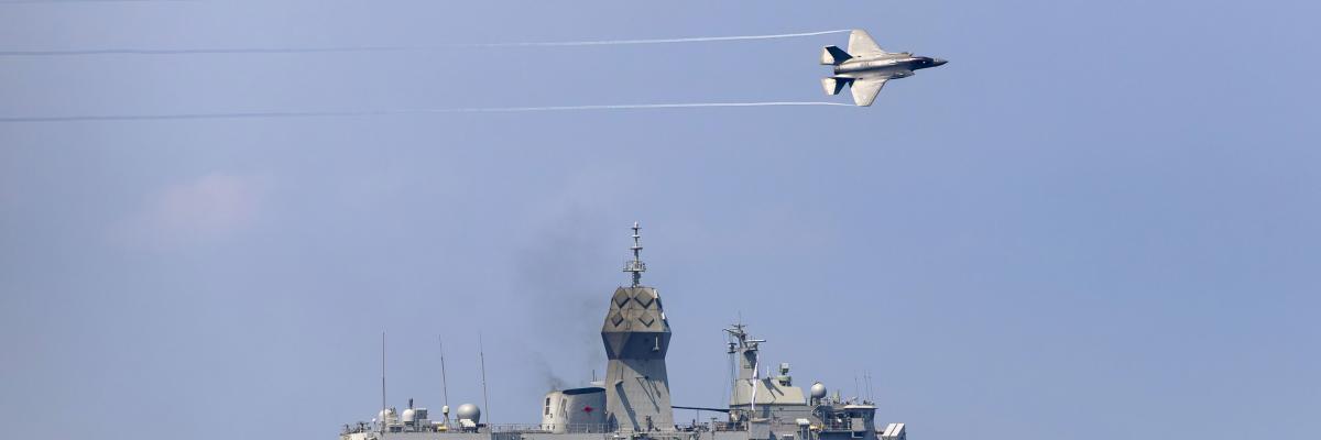 Naval ship with two planes flying overhead. 