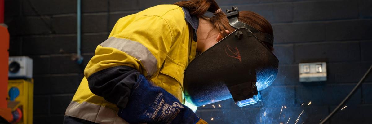 Female apprentice welding with mask on