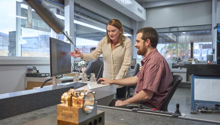 Women and man looking at computer screen smiling. 