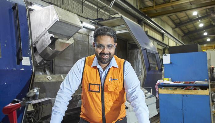 Hofmann Engineering employee smiling and holding CAD drawings