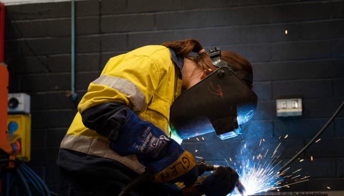 Female apprentice welding with mask on