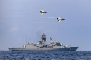 Naval ship with two planes flying overhead. 